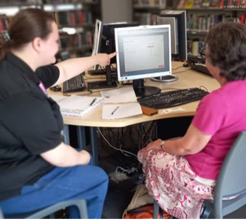 Library staff supporting user on PC